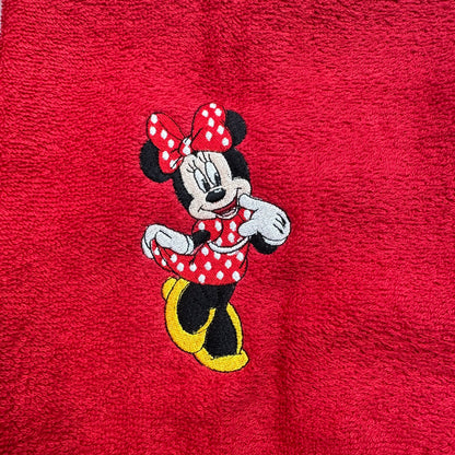A close-up of a red textured fabric featuring an embroidered Minnie Mouse character in the center.