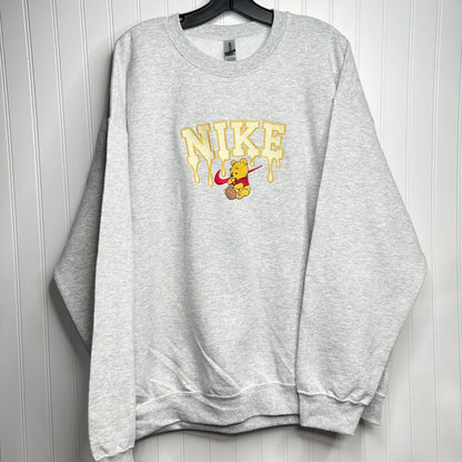 hanging gray sweatshirt with embroidered winnie the pooh with honey dripping from the nike logo