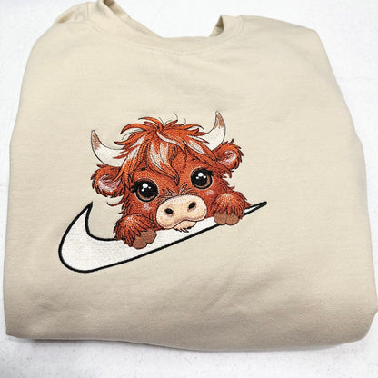 highland cow on nike swoosh on beige sweatshirt