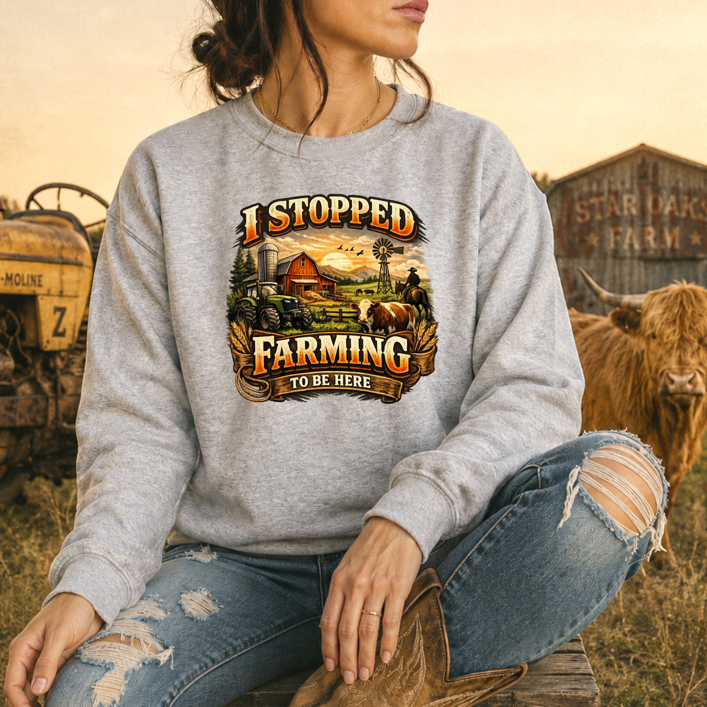 woman wearing gray sweatshirt with farm scene graphic that says I stopped farming to be here on it