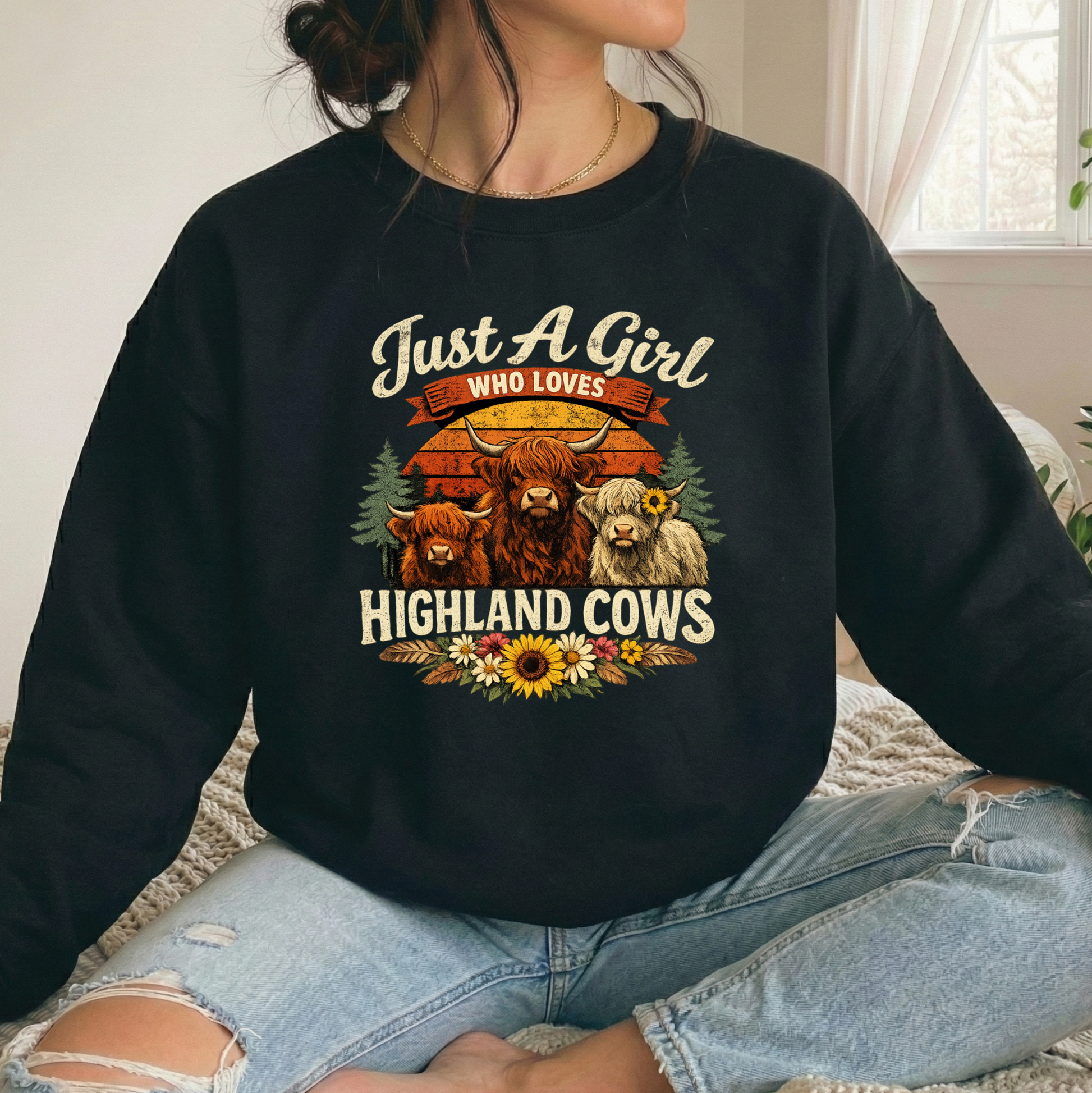 woman wearing a black sweatshirt with highland cows and flowers graphic that says just a girl who loves highland cows