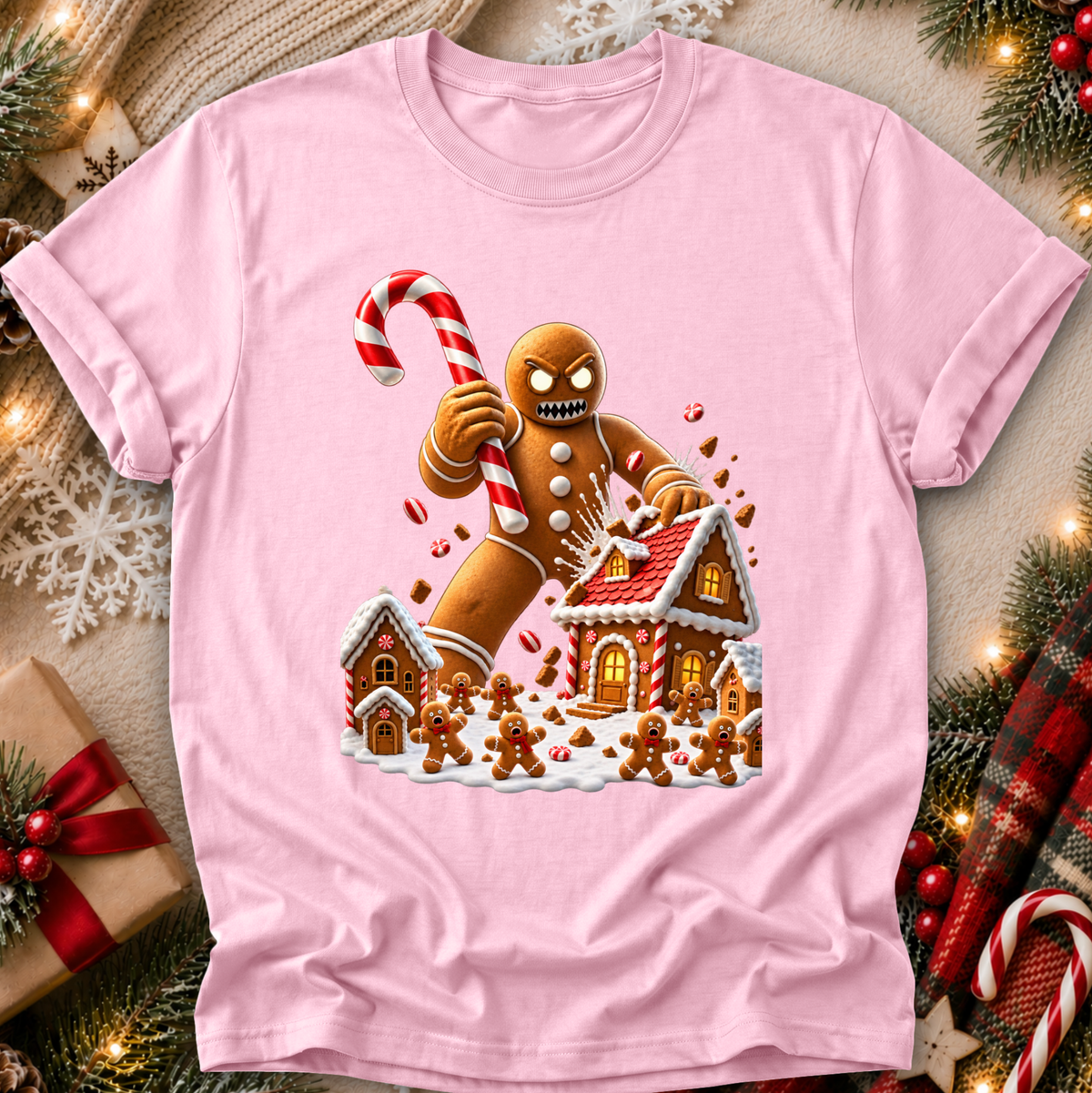 a light pink tshirt with a graphic design of an evil gingerbread man that is attacking a gingerbread town and other gingerbread people are screaming and running away and he's holding a giant candy cane