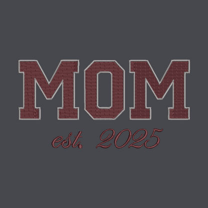 Embroidered-style text reading “MOM” in large maroon letters with a light outline, above smaller maroon script text reading “est. 2025,” on a dark gray background.