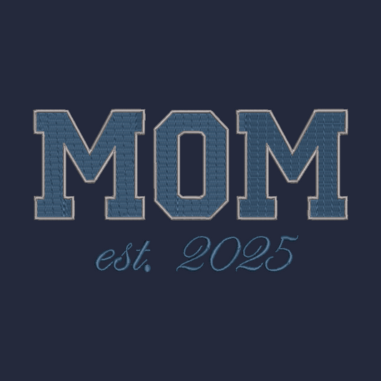 A dark navy blue graphic design featuring the word 'MOM' in large, textured varsity-style block letters outlined in light blue, with 'est. 2025' written below in a matching light blue script font.
