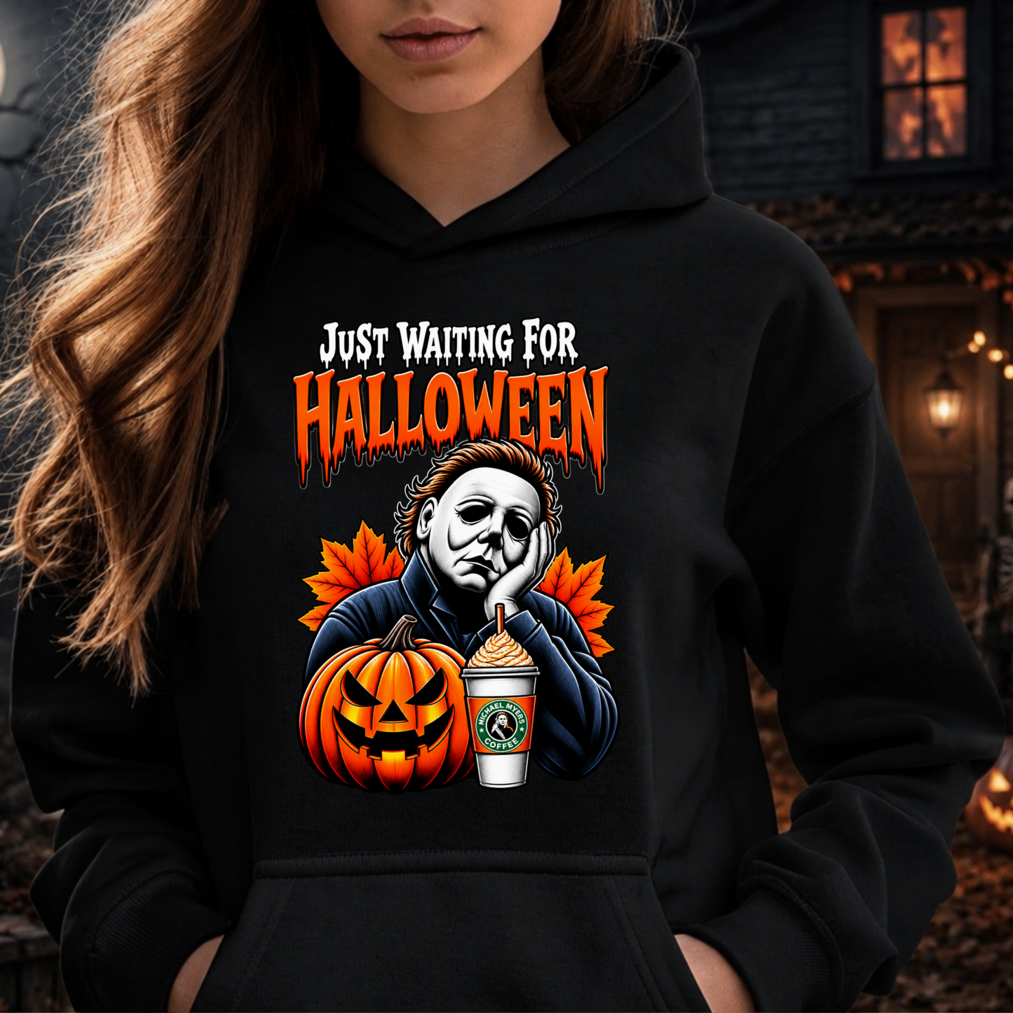 A woman wearing a black hoodie with a graphic print of Michael Myers, a jack-o'-lantern, autumn leaves, and a coffee cup, with the text 'JUST WAITING FOR HALLOWEEN' above the illustration.