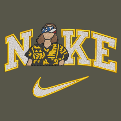 An embroidered graphic design featuring the word 'NIKE' in large white varsity-style letters with yellow outlines, with a stylized person wearing a patterned shirt and bandana in the center. Below the text is a white Nike swoosh with a yellow outline, all on a dark olive-gray background.
