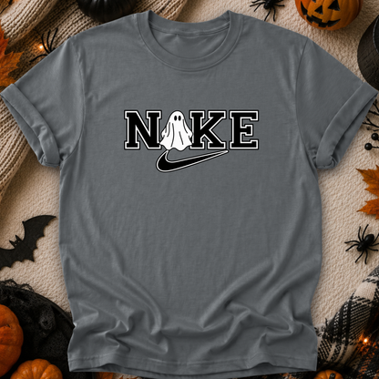 A gray short-sleeve t-shirt with a 'N O K E' graphic featuring a white ghost and a black swoosh, styled in a flat-lay with Halloween decorations.