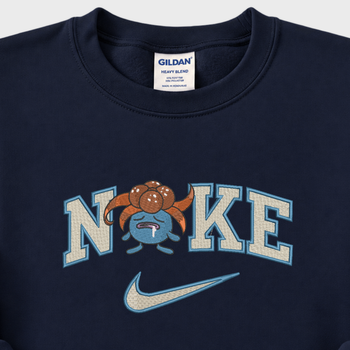 Close-up of a navy blue Gildan sweatshirt featuring a 'NIKE' graphic with a pokemon gloomy cartoon character and a light blue Nike swoosh.