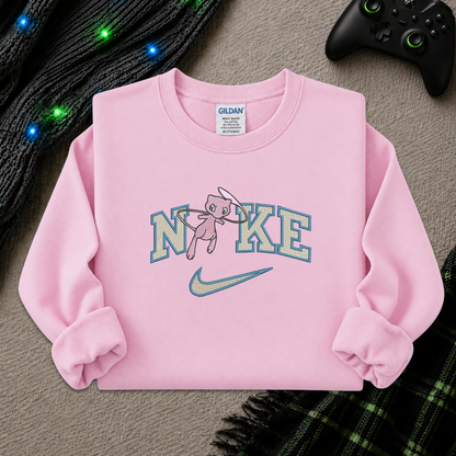 a light pink sweatshirt with an embroidered design of a pokemon mew character in the NIKE logo with a swoosh