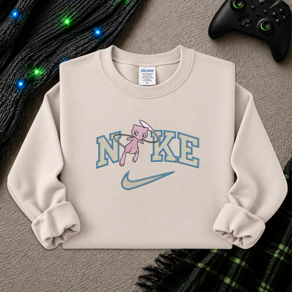 a beige sweatshirt with an embroidered design of a pokemon mew character in the NIKE logo with a swoosh