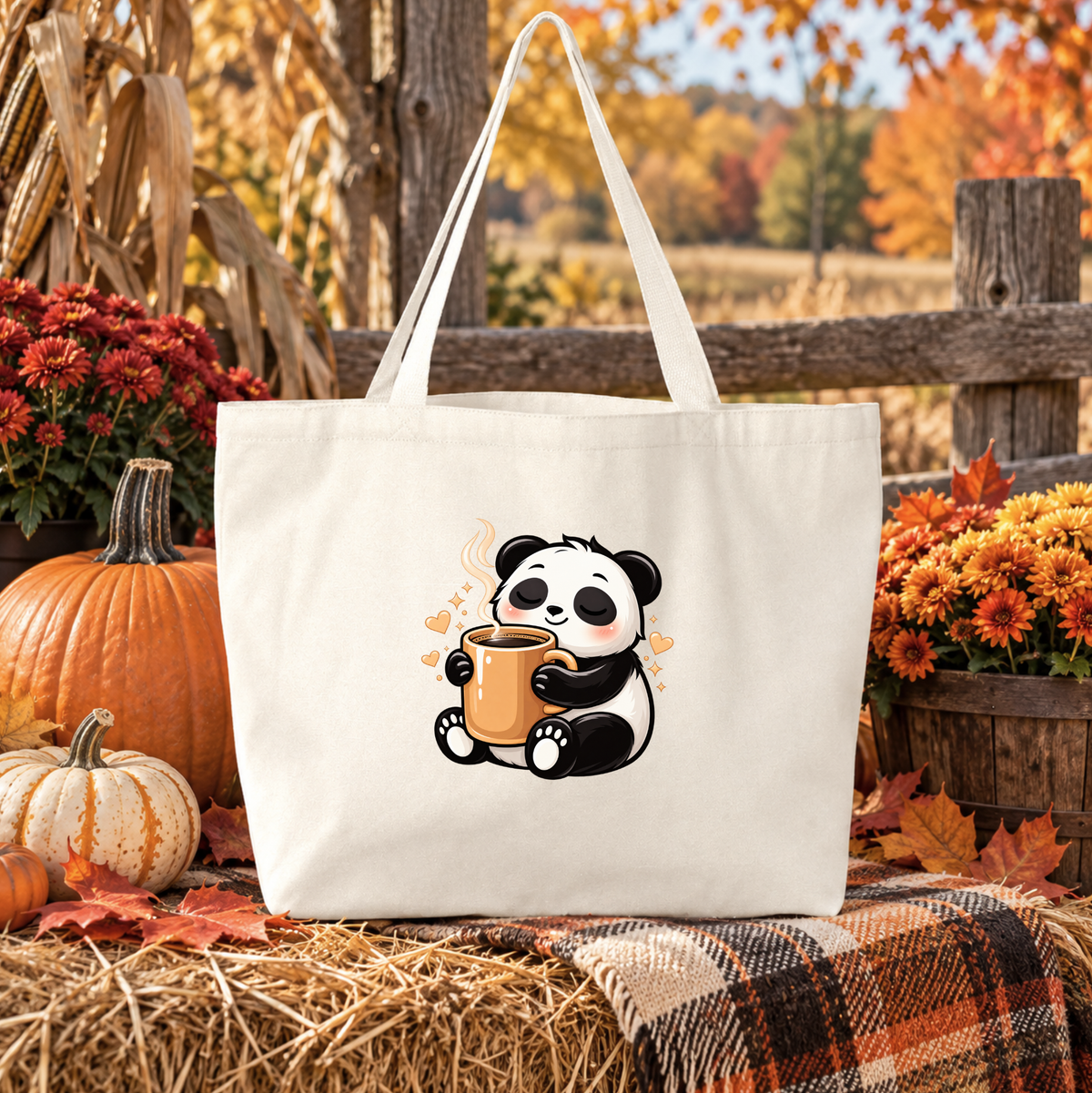 A cream canvas tote bag with a cute cartoon panda holding an orange mug, set against a rustic autumn background with pumpkins, flowers, and a plaid blanket.