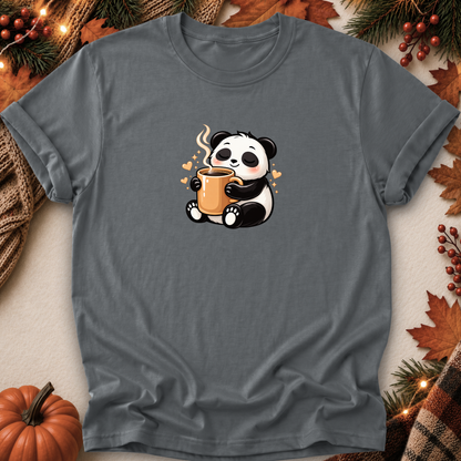A dark gray short-sleeve t-shirt with a cute cartoon panda holding an orange mug, styled in a flat-lay with autumn props like a pumpkin, pine branches, and leaves.