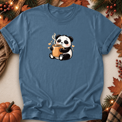 A slate blue crewneck t-shirt featuring a cute cartoon panda holding a steaming mug, styled in a cozy autumn flat-lay with a pumpkin, pine branches, and fall leaves.