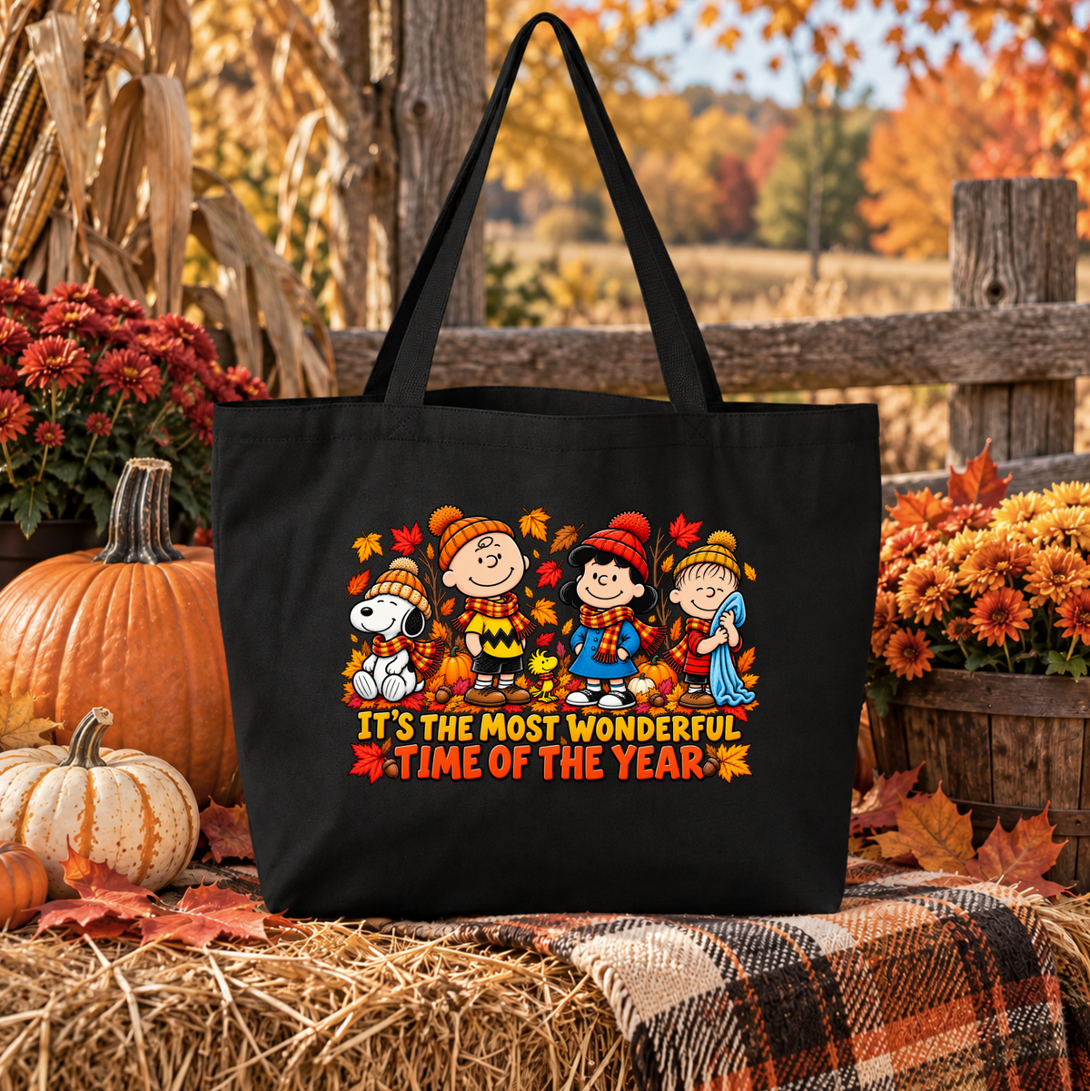 black canvas tote bag with a graphic of peanuts gang at fall time that says its the most wonderful time of year in an autumn pumpkin setting
