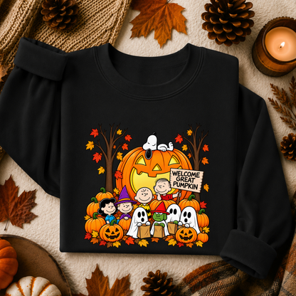 A black long-sleeve sweatshirt with a colorful Halloween graphic featuring Snoopy, Woodstock, Charlie Brown, Peppysub, ghosts, pumpkins, and a jack-o'-lantern that reads 'Welcome Great Pumpkin.' The sweatshirt is laid flat on a cozy autumn-themed background with leaves, pinecones, a candle, and burlap.