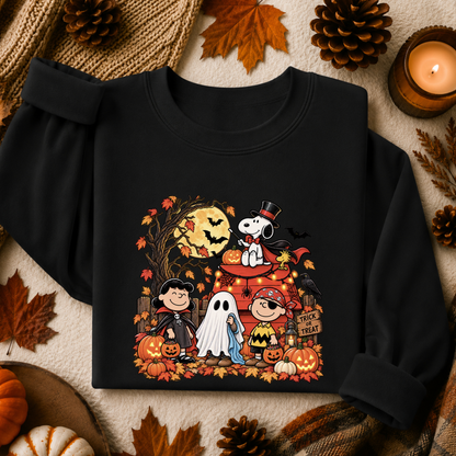 A black long-sleeve sweatshirt with a colorful Halloween graphic featuring Peanuts characters Snoopy, Woodstock, Charlie Brown, Lucy, and Bob, surrounded by autumn leaves, pinecones, and a candle.
