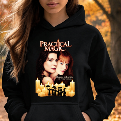 A woman wearing a black hoodie with a 'Practical Magic' graphic print featuring the movie title, two women's faces, candles, and silhouettes of witches, set against an autumn outdoor background.