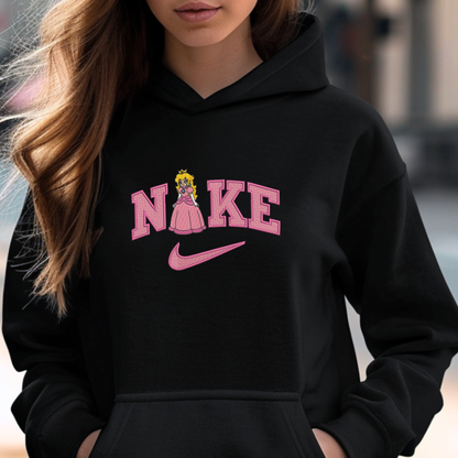 A woman wearing a black hoodie with a pink graphic that reads 'NIKE' styled like the Nike logo, featuring a cartoon princess peach inside the letter A and a pink swoosh underneath.