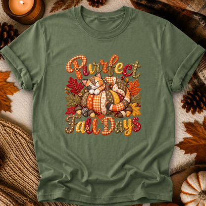 An olive green short-sleeve t-shirt with a cozy autumn graphic reading 'Purrfect Fall Days' around an illustration of a sleeping orange cat in a pumpkin, styled with fall leaves, pinecones, and a candle.