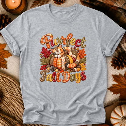 A heather gray short-sleeve t-shirt with a cozy autumn graphic reading 'Purrfect Fall Days' around an illustrated sleeping cat in a pumpkin body, surrounded by fall leaves and pinecones, shown in a styled flat-lay setting.