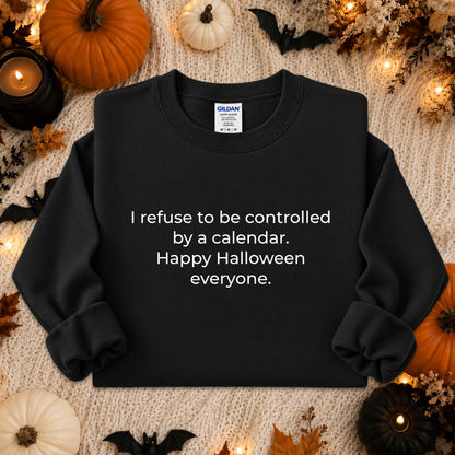 A black long-sleeve crewneck sweatshirt with white text reading 'I refuse to be controlled by a calendar. Happy Halloween everyone.