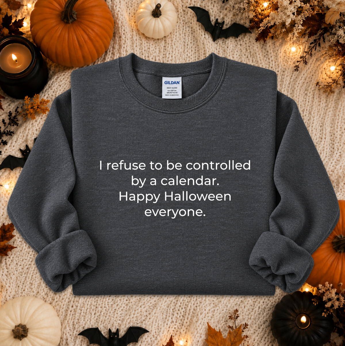 A dark heather gray crewneck sweatshirt with white text reading 'I refuse to be controlled by a calendar. Happy Halloween everyone.