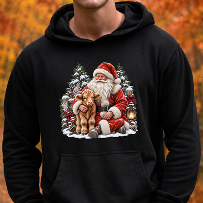 A person wearing a black pullover hoodie with a large Christmas graphic on the chest showing Santa Claus hugging a brown calf, set against a blurred autumn background.