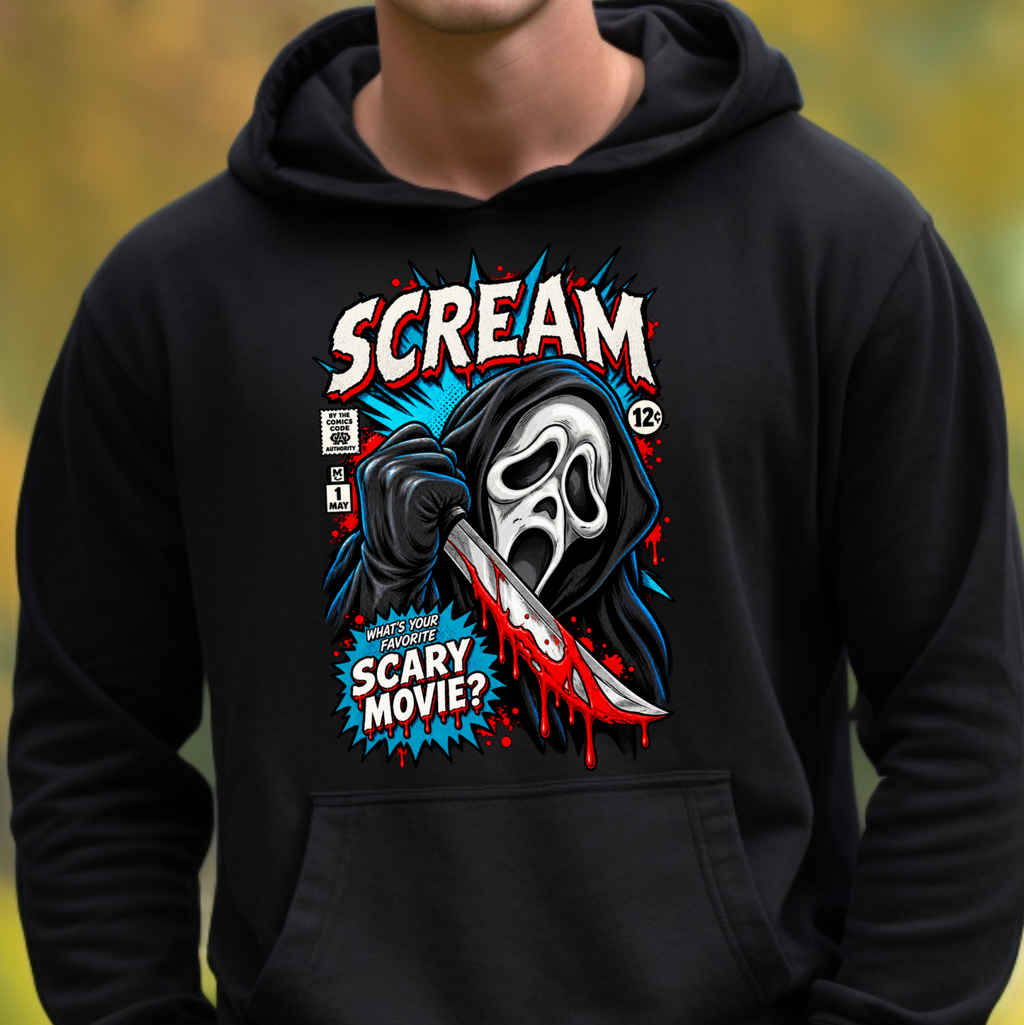 A person wearing a black hoodie with a large horror-themed graphic on the chest. The design features the word 'SCREAM' in distressed white letters, a hooded ghostly figure holding a bloody knife, and comic-style text reading 'WHEN YOU'RE SCARY, SCARY MOVIE?' The background is softly blurred in warm yellow-green tones.