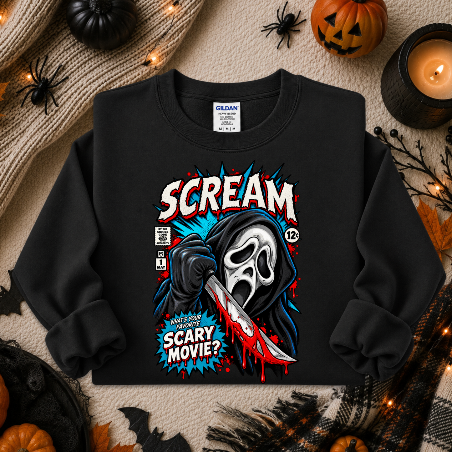 A black long-sleeve crewneck sweatshirt featuring a comic-book style graphic of Ghostface holding a knife, with the text 'SCREAM' and 'SCARY MOVIE?'. The sweatshirt is displayed in a flat-lay Halloween setting with pumpkins, a candle, and spider decorations.