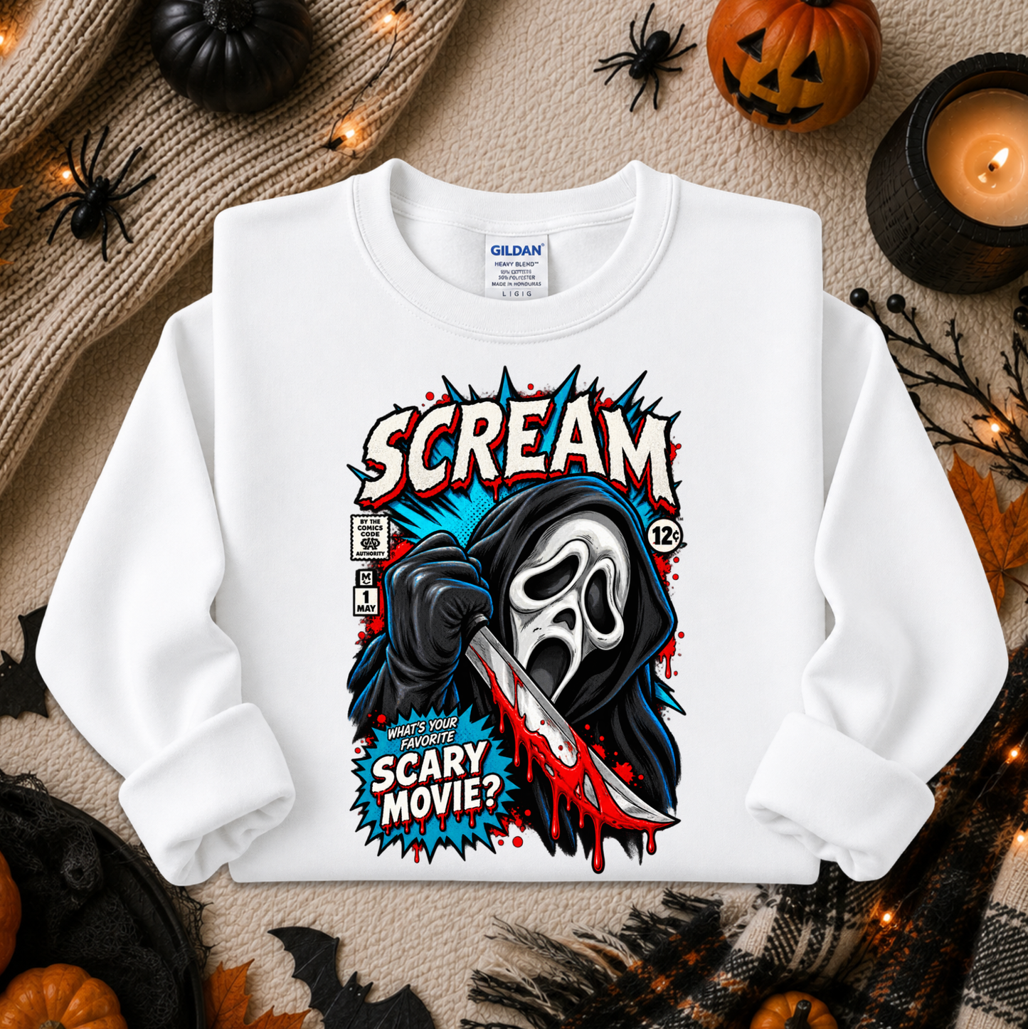 A white long-sleeve crewneck sweatshirt with a graphic print of the Ghostface comic book character holding a bloody knife, surrounded by Halloween decorations including pumpkins, a candle, and spiderwebs.