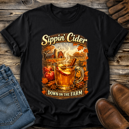 black tshirt with fall autumn farm scene with a glass of apple cider graphic that says sippin cider down on the farm