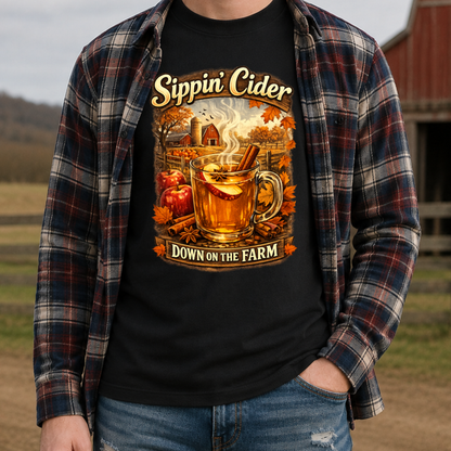 man wearing a black tshirt with fall autumn farm scene with a glass of apple cider graphic that says sippin cider down on the farm