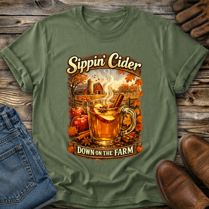 green tshirt with fall autumn farm scene with a glass of apple cider graphic that says sippin cider down on the farm
