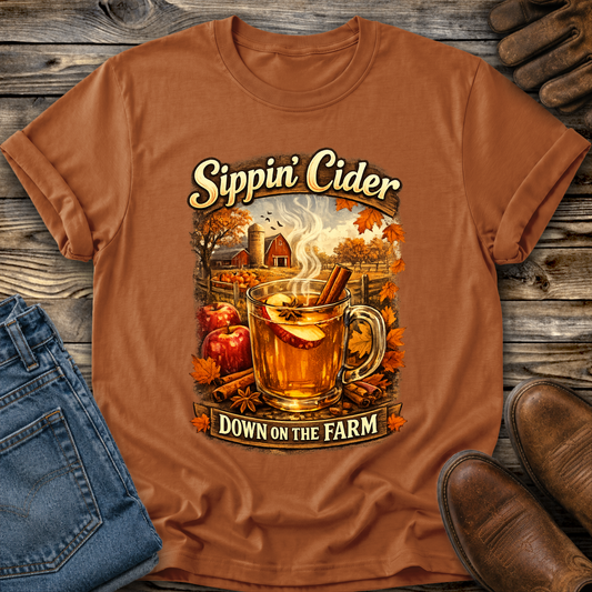 orange tshirt with fall autumn farm scene with a glass of apple cider graphic that says sippin cider down on the farm