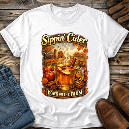 white tshirt with fall autumn farm scene with a glass of apple cider graphic that says sippin cider down on the farm