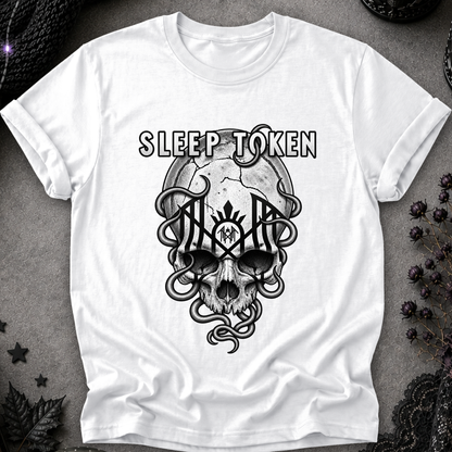 A white short-sleeve crewneck t-shirt featuring a black graphic print of a skull, snakes, and the text 'SLEEP TOKEN' on the front, laid flat on a textured gray background with gothic decorative props.