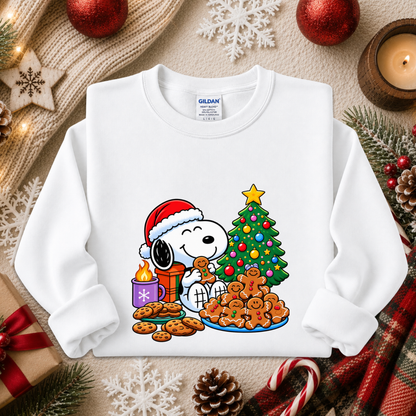 A white Gildan sweatshirt featuring a colorful graphic of Snoopy and Woodstock by a Christmas tree, styled in a festive flat-lay with holiday decorations.