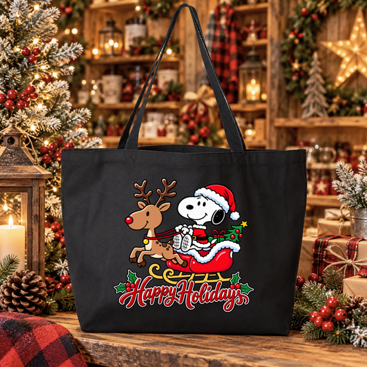 a black canvas tote bag with a christmas graphic of snoopy riding in santa's sleigh in his costume pulled by a reindeer and says happy holidays