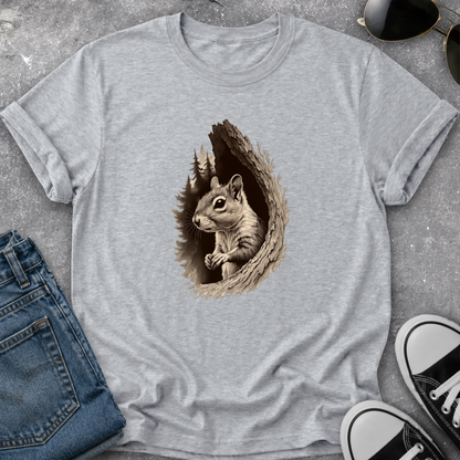 A light heather gray t-shirt featuring a detailed graphic of a squirrel peeking out of a tree hollow, styled in a flat-lay with jeans, sunglasses, and sneakers on a gray concrete background.