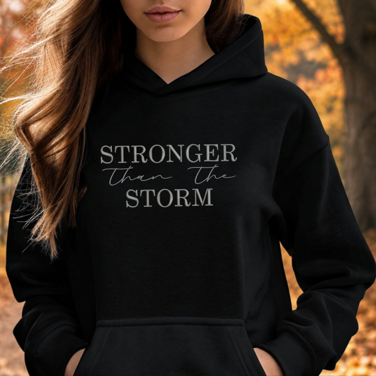 black sweatshirt with the text Stronger Than The Storm embroidered on it
