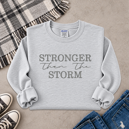 light gray sweatshirt with the text Stronger Than The Storm embroidered on it