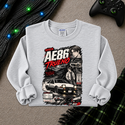 A light gray long-sleeve crewneck sweatshirt with a detailed graphic print of the Toyota AE86 Trueno from the movie Initial D, styled flat on a textured gray surface with a black controller, a knit sweater, and a plaid blanket.