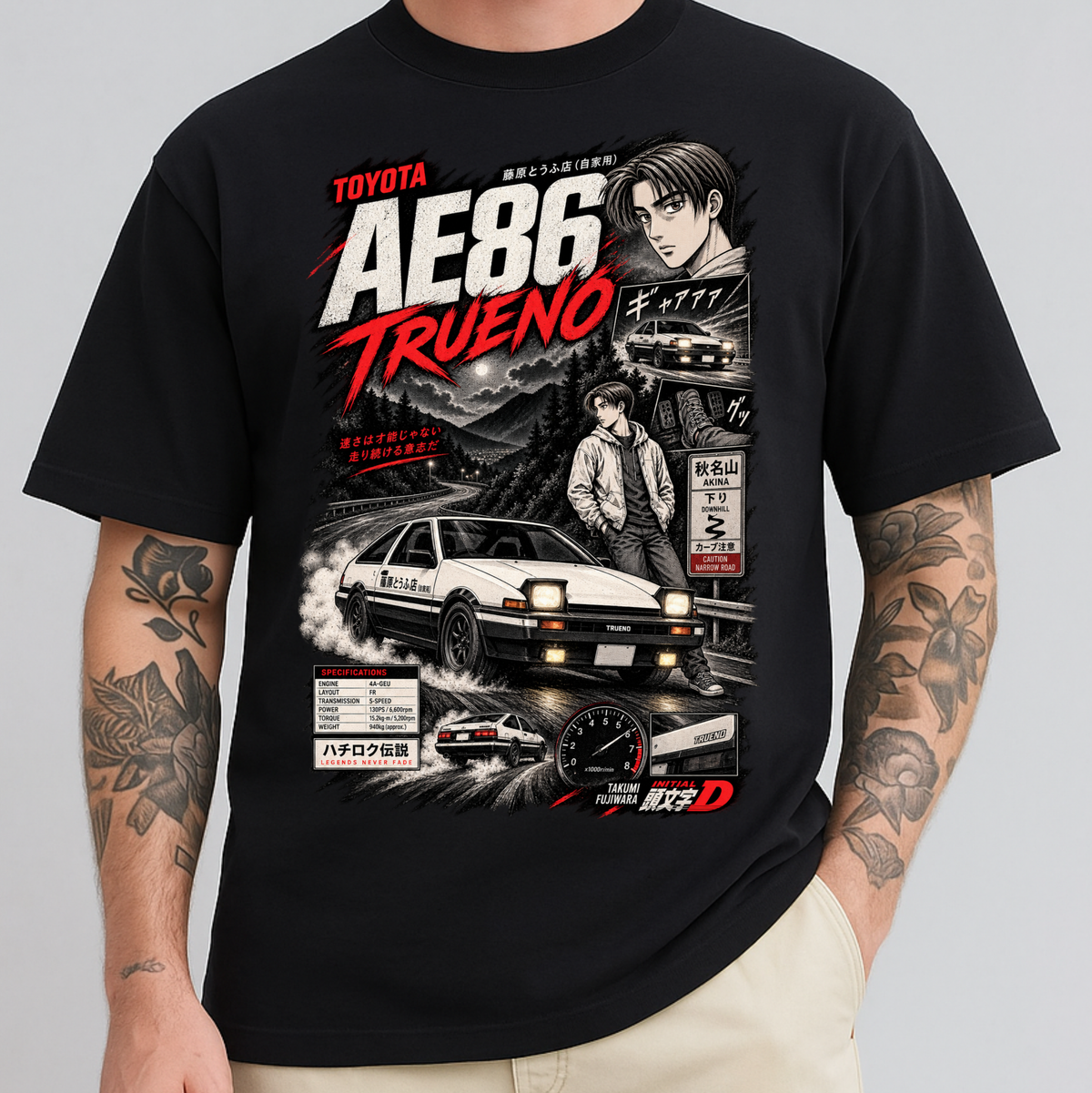 A man wearing a black graphic t-shirt featuring a detailed print of the Toyota AE86 Trueno from the movie Initial D. The graphic includes a white race car, a driver character, and Japanese text.