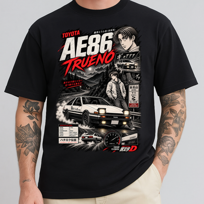 A man wearing a black graphic t-shirt featuring a detailed print of the Toyota AE86 Trueno from the movie Initial D. The graphic includes a white race car, a driver character, and Japanese text.
