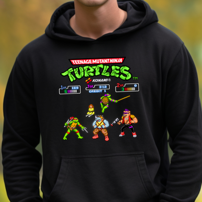A person wearing a black hoodie with a colorful Teenage Mutant Ninja Turtles video game-style graphic on the chest, including the Konami logo and character illustrations, against a blurred outdoor background.