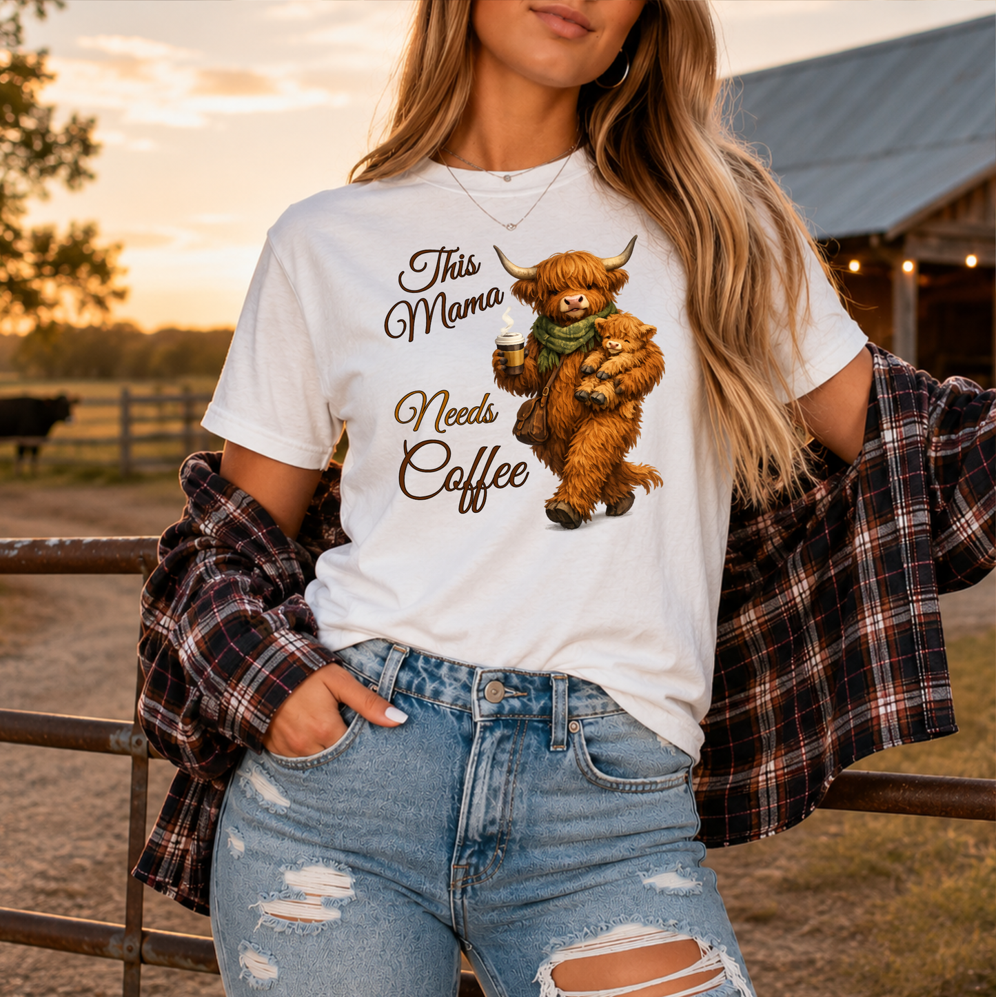 woman wearing a white tshirt with a highland cow holding her calf and a cup of coffee that says this mama needs coffee