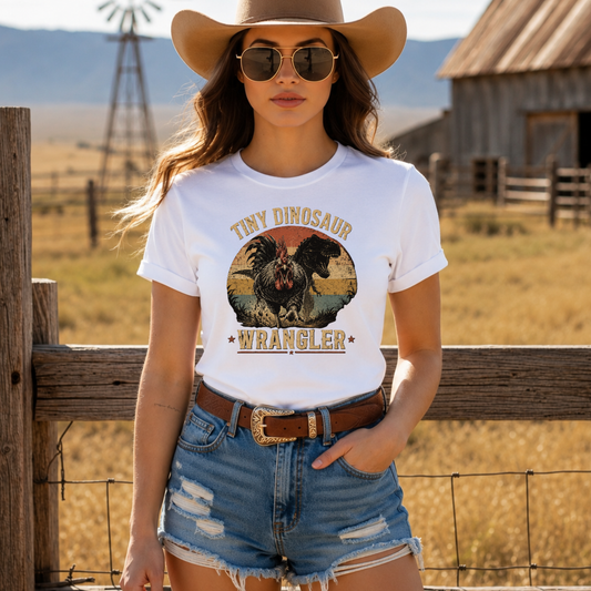 woman wearing a white tshirt with a distressed graphic of a angry chicken and dinosaur that says tiny dinosaur wrangler