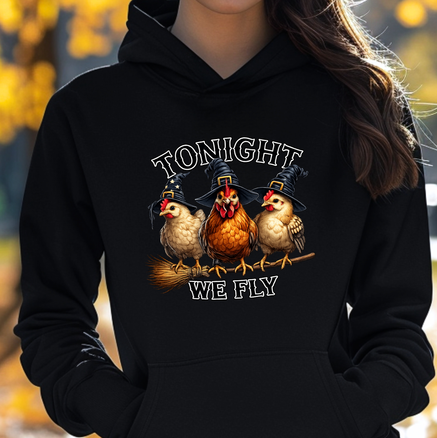 woman wearing a black sweatshirt with funny chicken witches on a broomstick graphic design that says tonight we fly