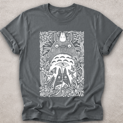 A dark gray crewneck t-shirt featuring a detailed white line art graphic of Totoro and other My Neighbor Totoro characters surrounded by foliage, laid flat on a textured light gray background.