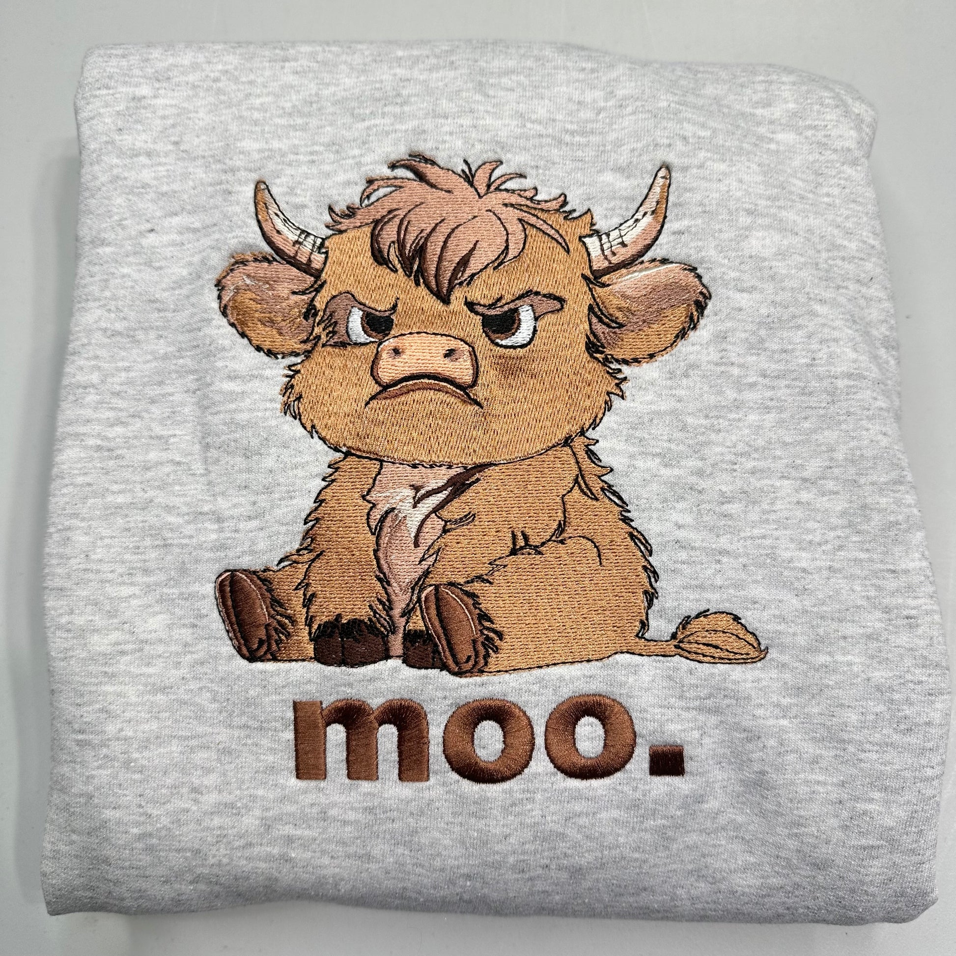 embroidered highland cow with text on a gray sweatshirt
